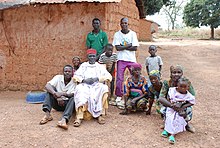 Plusieurs personnes tchadiennes, dehors, devant une hutte en terre cuite