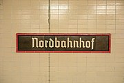 Bahnhofsschild in Schriftart Tannenberg an einer Hintergleiswand, 2023