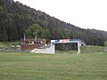 Una pasarela de hormigón y un edificio de madera a la izquierda.