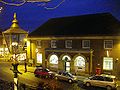 photo of the post office taken at evening time. A gas lantern stands in the foreground. (from Malvern, Worcestershire)