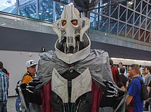 Homme portant un masque de cyborg et des vêtements gris.
