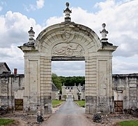 Photographie en couleurs d'un portail aux montants et au tympan en pierre sculptée.