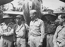 Askeri bir uçağın önünde hafif üniformalı beş adamın siyah beyaz fotoğrafı.