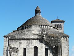 Photo représentant la partie supérieure du chevet de l'église Saint-Étienne-de-la-Cité, sur fond de ciel bleu. Au-dessus, un lanternon surmonte une coupole large de plus de la moitié de l'édifice. À l'arrière sur la droite, on peut voir le clocher carré.