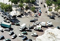 Verkeer doorkruist elkaar op het Place de l'Étoile. Dit ronde plein zonder lijnen omringt de Arc de Triomphe op de kruising van 12 wegen.