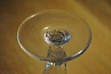 The underside of a conical foot on an 18th century (c1780) dwarf ale glass. This shows a broken pontil mark, air bubbles and a tiny inclusion of grit. Plain foot (broken pontil)..jpg