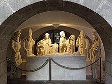 Fotografía de un grupo tallado en piedra blanca que representa la sepultura de Cristo