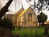 Looking west through the trees at the east chancel gable in warm evening sunshine