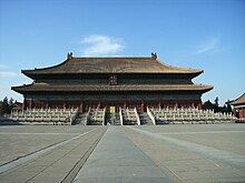 Photo couleur prise de face par une journée ensoleillée d'un bâtiment majestueux de style chinois avec un double toit.  La plaque sur le bâtiment dit "Taimiao" ("temple impérial ancestral") en chinois et en mandchou.  Le temple est placé sur une plate-forme surélevée et entouré de trois couches de clôtures blanches placées à différentes hauteurs.  Trois volées d'escaliers différentes mènent au bâtiment.