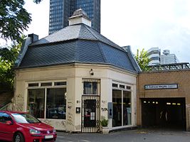 Sortie est de la gare S-Bahn vers Berlinickestrasse avec le pavillon de vente classé de 1910. La tour du rond-point Steglitz est visible derrière le toit.