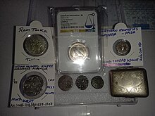 A collection of various collectible coins, including several Indian silver coins and an American Innovation dollar graded by NGC, alongside a vintage sterling silver case. A little collection of precious coins, coin slab, fountain pen, and silver box, photographed in West Bengal, India, December 24, 2023.jpg