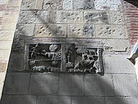 Deux scènes sont sculptés sur une pierre. À gauche, un homme tenant un bâton et conduisant des boeufs ? dessous deux chiens. À droite, un berger et son troupeau de chèvres