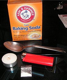 For cocaine (in a plastic bag at bottom) to be converted to crack, several supplies are needed. Pictured here are baking soda, a commonly used base in making crack, a metal spoon, a tealight, and a cigarette lighter. The spoon is held over the heat source to "cook" the cocaine into crack. Crack Ingredients.JPG