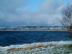 Roztržené jezero obklopené zasněženými poli