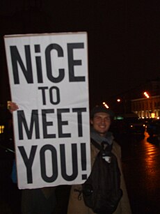 A protestor holds up a placard which reads: 'Nice to meet you!' Imagem: Lvova Anastasiya.