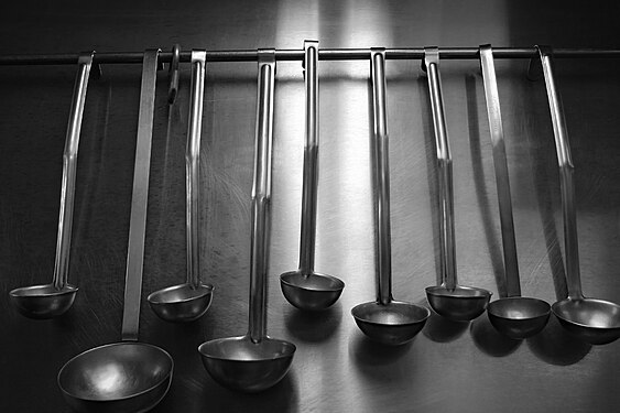 Set of serving ladles on hanger on stainless kitchen wall