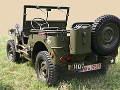 Left rear quarter view of a Willys MB with split combat rims, a spare gas can, and a spare wheel