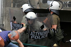 29 Ιουνίου 2011: Επίθεση των ΜΑΤ για τερματισμό του αποκλεισμού της Λεωφόρου Βασιλίσσης Σοφίας (στο ύψος της Ερατοσθένους) από διαδηλωτές οι οποίοι προσπαθούσαν να αποκλείσουν την πρόσβαση βουλευτών στην βουλή. Στιγμιότυπο κατά την διάρκεια της επίθεσης όπου οι δυνάμεις των ΜΑΤ επιτίθενται σε ηλικιωμένο διαδηλωτή