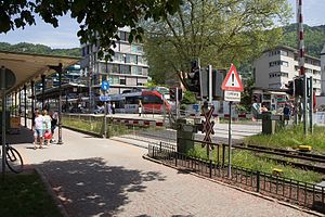 Gray-and-red train at island platform; a grade crossing links the ferry terminal to Seestraße