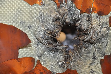 An exit hole through Kevlar–Nextel fabric after hypervelocity testing of the multilayer shielding for ESA’s ATV space freighter, simulating an impact by space debris.