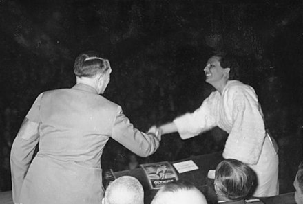 Uraufführung von Olympia, Hitler schüttelt Riefenstahl die Hand; auf dem Pult das Filmheft