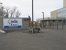Photo de l'accès de la centrale. Une bannière EDS est affichée sur la clôture en treillis métalalique.