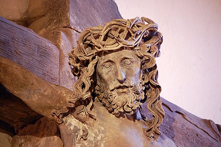 Photographie d'un Christ en croix dont on ne voit que la tête couronnée d'épines, les yeux fermés.