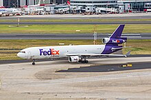 A McDonnell Douglas MD-11F of FedEx Express taxiing to the cargo terminal at Sydney Airport; Terminal 3 is in the background