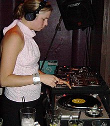A DJ mixing two record players at a live event FemaleDJ.jpg