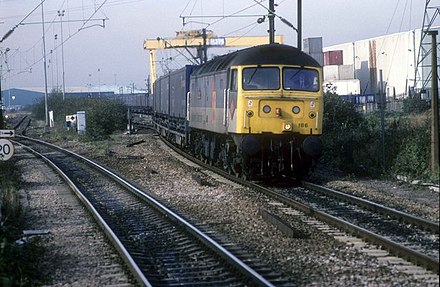 In October 1995, a Class 47 train departs Ripple Lane. The cranes of the depot can be seen in the background.
