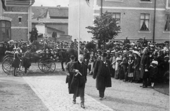 Örebroutställningen 1911. Konung Gustav V anländer till utställningen. Bakom Gustav V går Prins Eugen i plommonstop (kubbhatt) och till höger går fabrikör Anton Hahn i cylinderhatt (hög hatt).