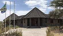 Ein Blick auf den Vordereingang des Olduvai Gorge Museum mit einer tansanischen Flagge auf einem Fahnenmast vor dem Gebäude.