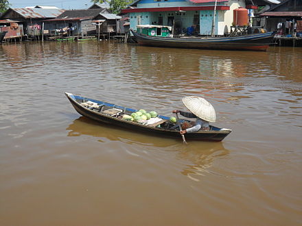 A woman using a wooden boat to go to the floating market