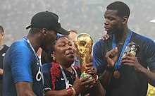 Pogba (right) with his brother Florentin and their mother, holding the World Cup trophy after the 2018 FIFA World Cup final Paul Pogba World Cup Trophy.jpg