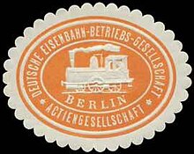 An orange and offwhite seal in the shape of an oval with an image of a train in the center with the word "Berlin" written under. Circled by the text of the German name of the company.