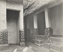 photo en noir et blanc d'une structure architecturale dont les piliers comportent des symboles ashanti en bas-relief