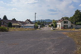 Une route bordée de deux rangées de maisons avec une grande colline en arrière plan.