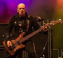 Tony "Demolition Man" Dolan (pictured in 2013) fronted the band from 1989 to 1992. Demolition Man - Mpire of Evil (2013).jpg