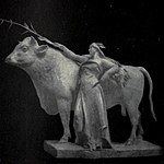 Statua di una donna che tiene una pianta di mais appoggiata a una mucca