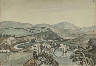 Four-arched stone bridge over river, looking towards a town, hills in the background