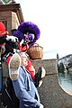 Gugge at Mittlere Brücke during Cortège of Basler Fasnacht putting feet on audience member by Sparrow (2019)