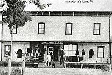 Une photographie ancienne d'un bâtiment portant les inscriptions « Canada », « J. M. Hill » et « U.S.A. ».