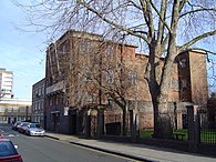 toont een blik van buitenaf op Kingsley Hall, een bakstenen gebouw, in Londen