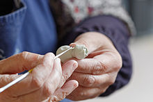 The hands of a person, shaping a lump of white paste