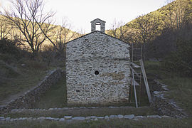 Parete della chiesa incorniciata da muretti.  Il terreno vicino alla chiesa è più basso di quello secondo i muretti.