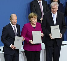 Olaf Scholz, Angela Merkel und Horst Seehofer bei der Unterzeichnung des Koalitionsvertrages (2018) (Quelle: Wikimedia)