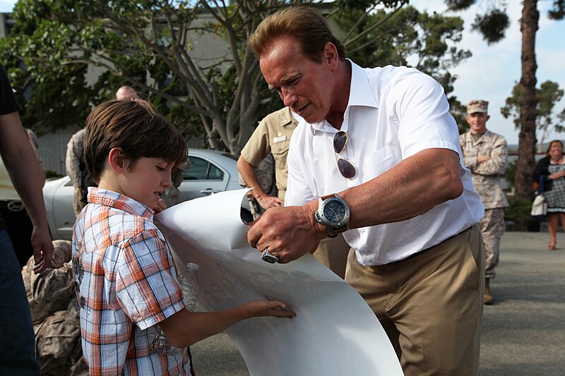 File:Arnold Schwarzenegger signs a young boy’s “The Expendables 2” poster, 2012.jpg