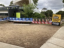 Election posters at a polling place, including one by the Liberals on the Labor government's cuts to local road funding Aston by-election Wattleview Primary April 2023 1.jpg