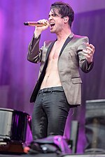 Brendon Urie tritt in einer braunen Jacke auf der Bühne auf.