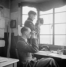 The duty officer in the tower at RAF Catfoss in Yorkshire keeps watch while an airman signals to an aircraft using an Aldis lamp, April 1941. Catfoss was home to No 2 (Coastal) OTU Royal Air Force 1939-1945- Coastal Command CH2465.jpg